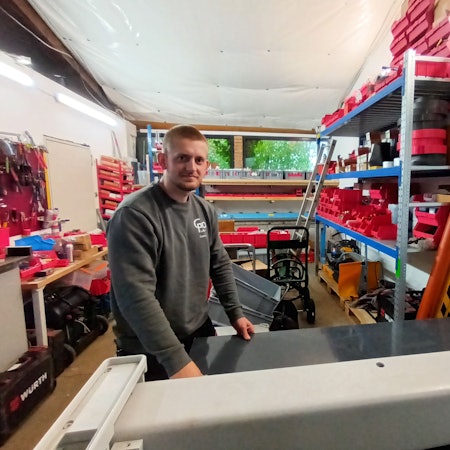 Ein Mann steht in einer Werkstatt an einer Schneidemaschine