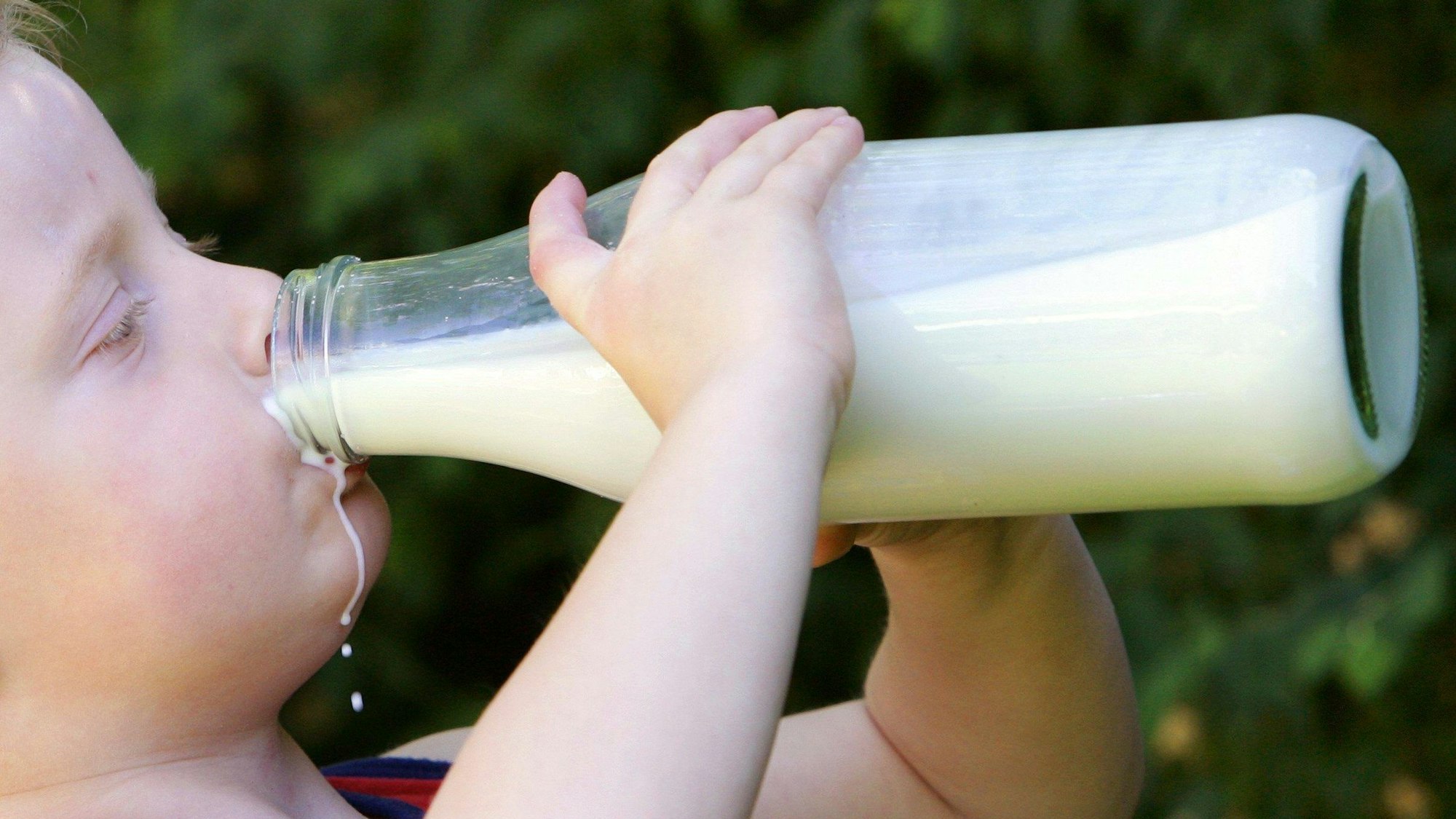 Ein kleiner Junge trinkt aus einer Milchflasche.