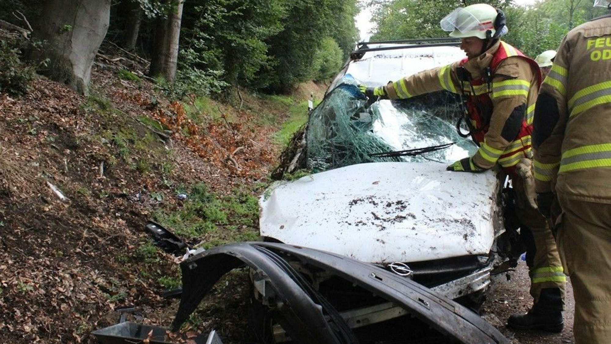 Feuerwehrleute stellen einen weißen Opel, der auf der Seite lag, wieder auf die Räder.