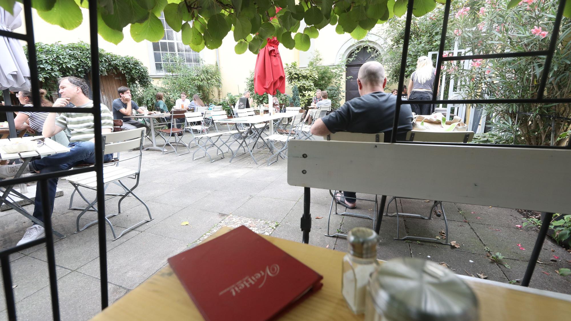 Blick in einen Innenhof, in dem Tische und Stühle eines Cafés stehen.