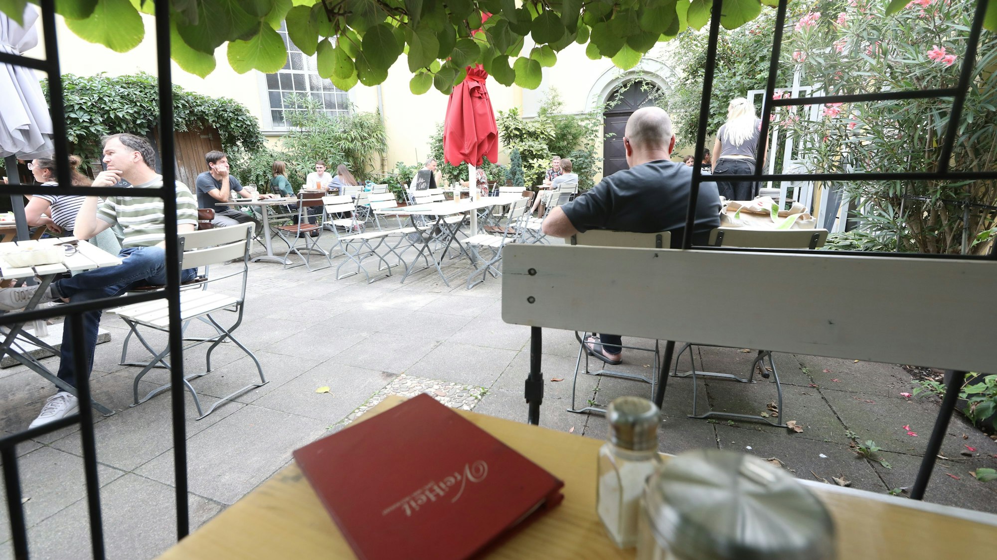 Blick in einen Innenhof, in dem Tische und Stühle eines Cafés stehen.