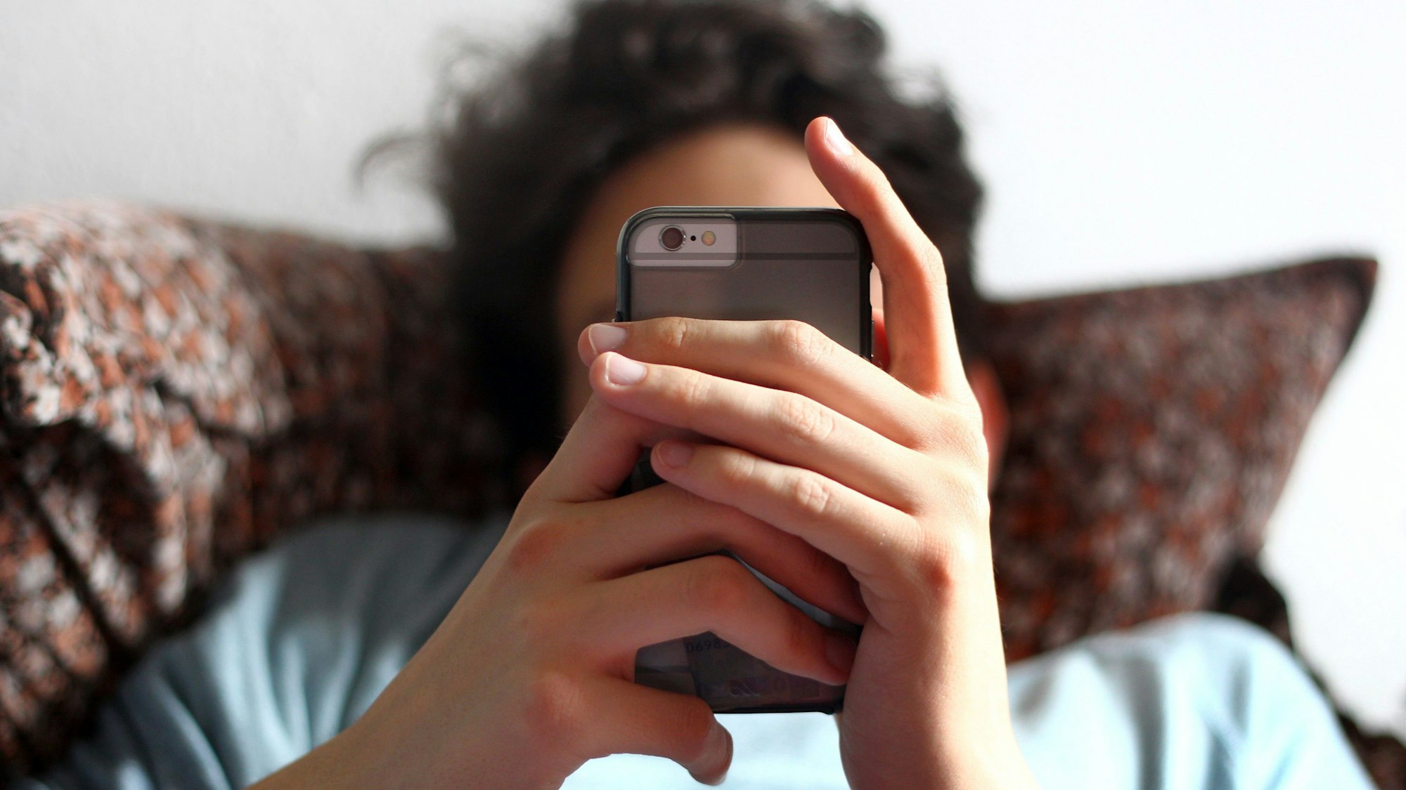 Ein junger Mann blickt auf ein Smartphone.