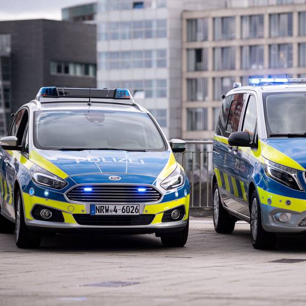 Zwei Polizeiwagen stehen auf einem Grundstück.