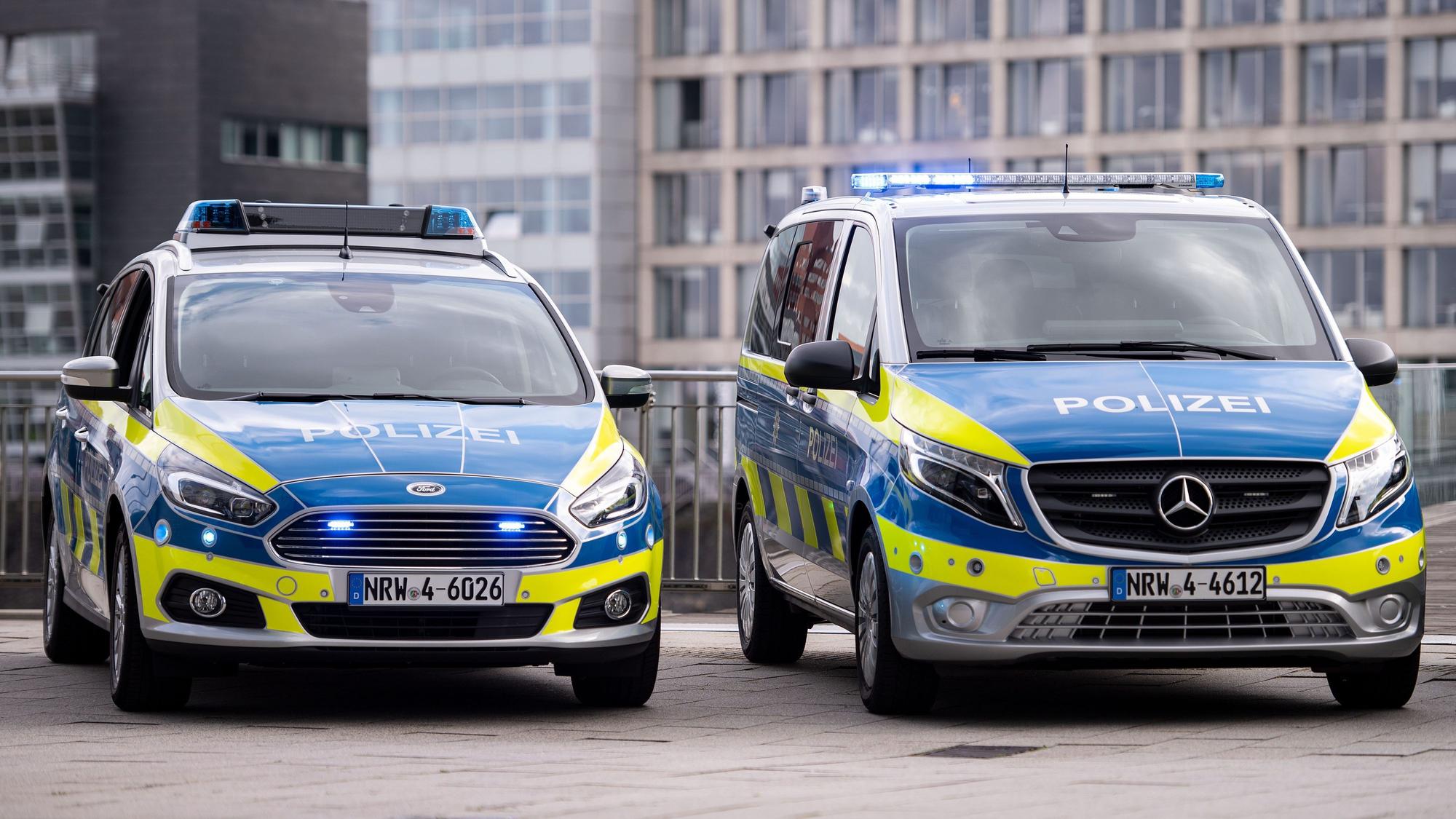 Zwei Polizeiwagen stehen auf einem Grundstück.
