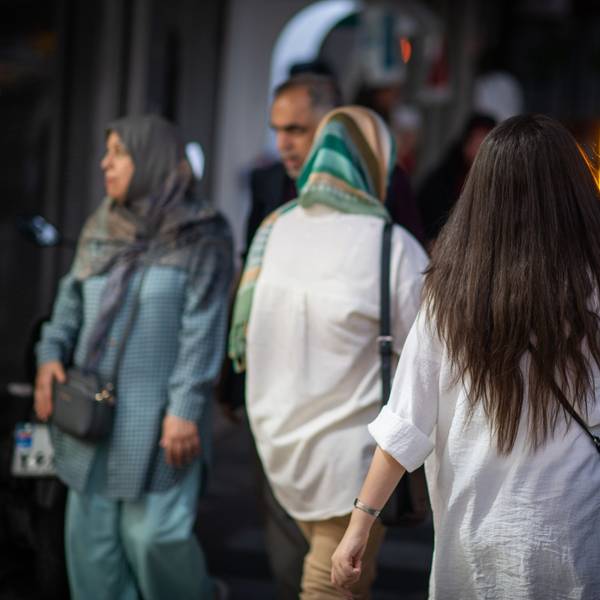 10.07.2023, Iran, Teheran: Eine Frau läuft in Teheran mit offenen Haaren am Abend eine Straße entlang.