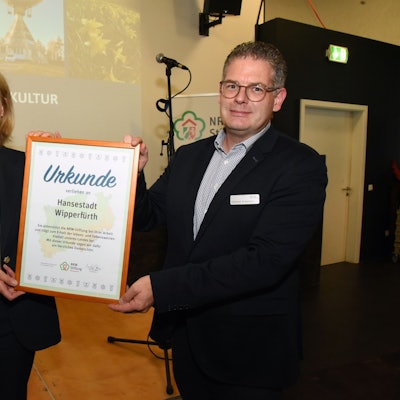 Ein Mann und eine Frau halten eine große Urkunde in Händen.