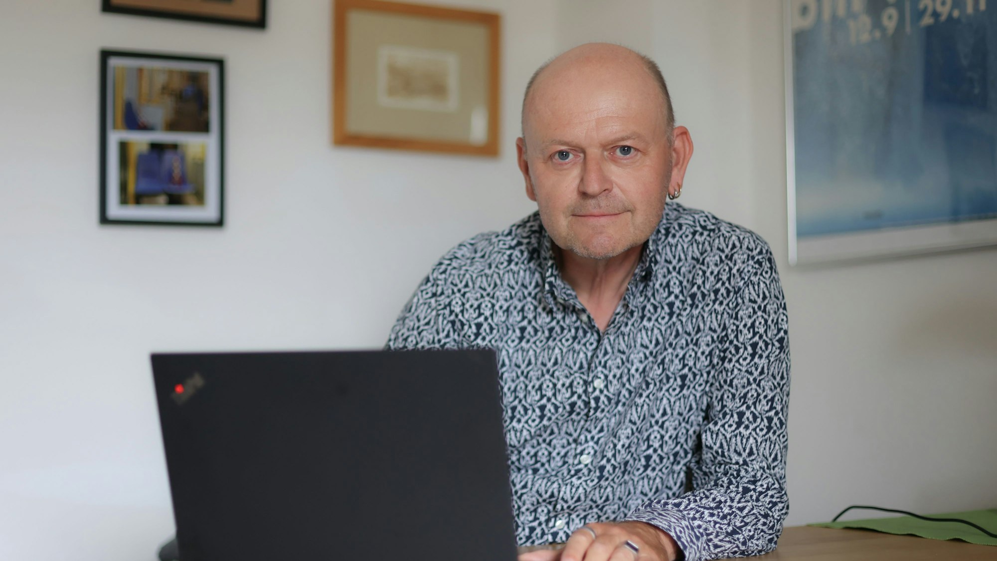 Der Kölner Christian Erichsen sitzt mit einem Laptop am Tisch.