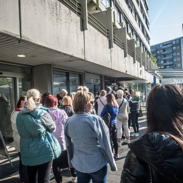Menschen stehen vor einem Gebäude in einer Warteschlange.
