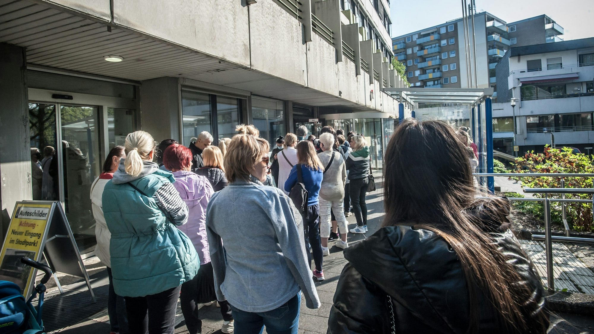 Menschen stehen vor einem Gebäude in einer Warteschlange.