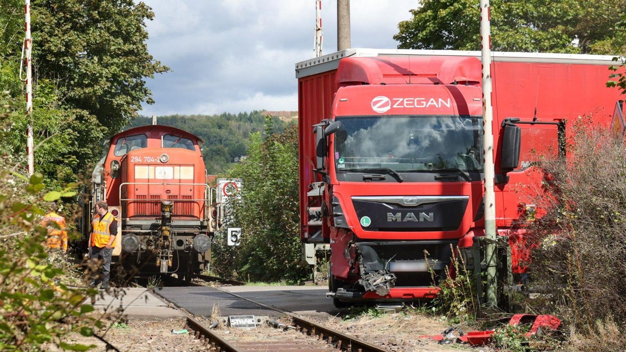 Rettungskräfte sind am Bahnübergang nach einem Unfall zwischen einem unbeladenem Güterzug und einem Sattelschlepper im Einsatz. Beim Aufprall eines Lastwagens auf einen Güterzug im saarländischen Schmelz (Landkreis Saarlouis) ist der Lkw-Fahrer verletzt worden.