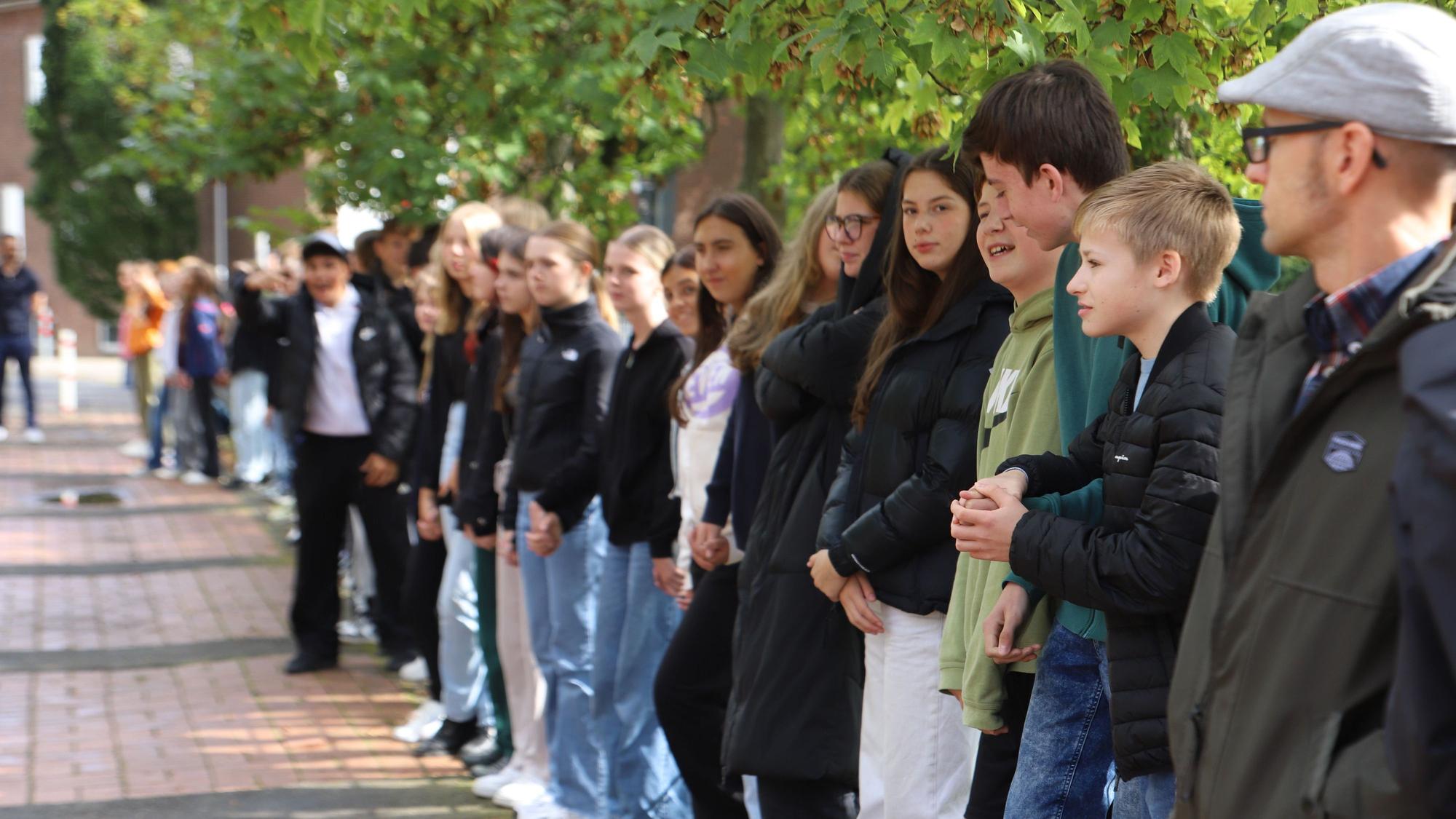 Schülerinnen und Schüler stehen in einer Reihe.