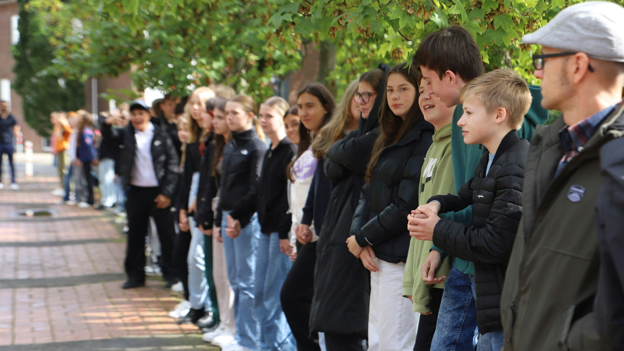 Schülerinnen und Schüler stehen in einer Reihe.