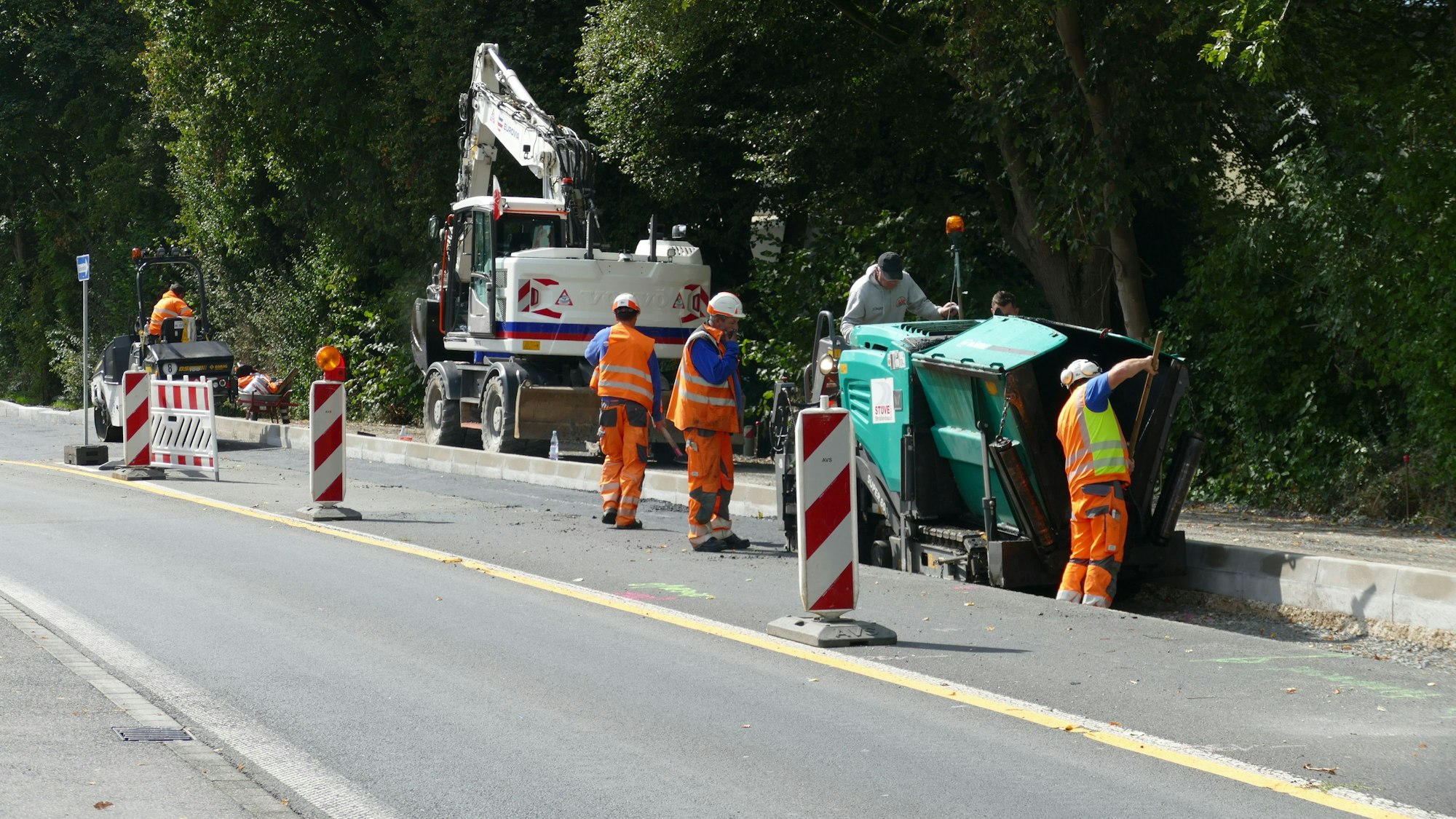 Straßen-Baustelle mit Baufahrzeugen, Absperrungen und Arbeitern