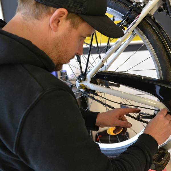 Ein Mann kontrolliert die Kette eines Fahrrads.