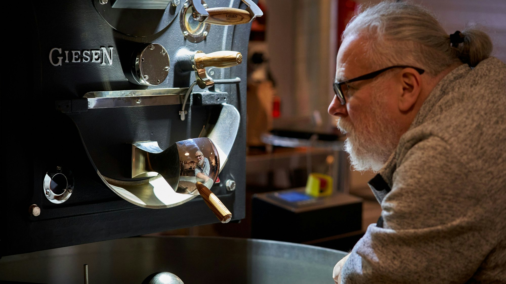 Ein Mann steht vor einer Röstmaschine.