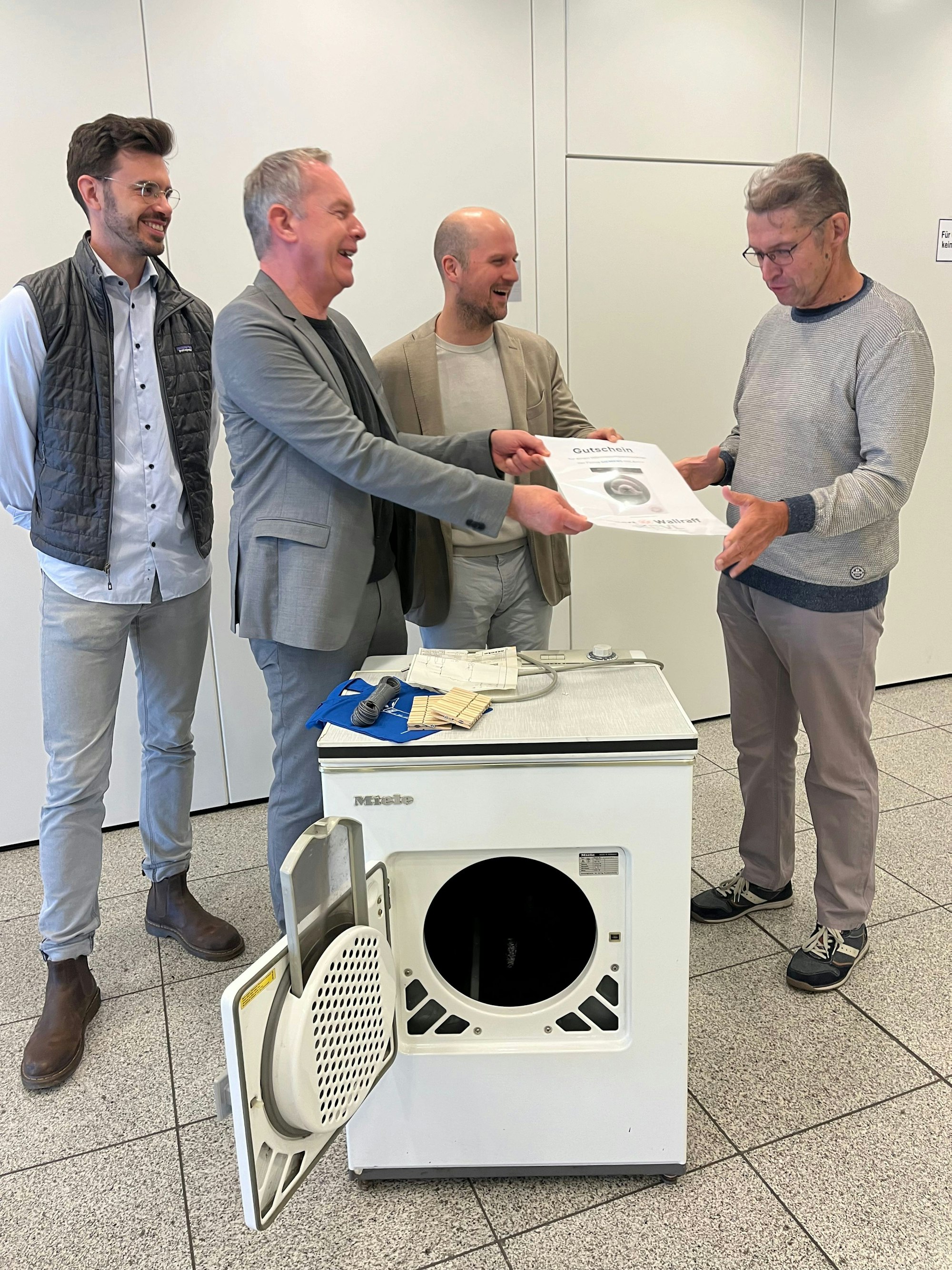 Vier Männer mit einem alten Wäschetrockner