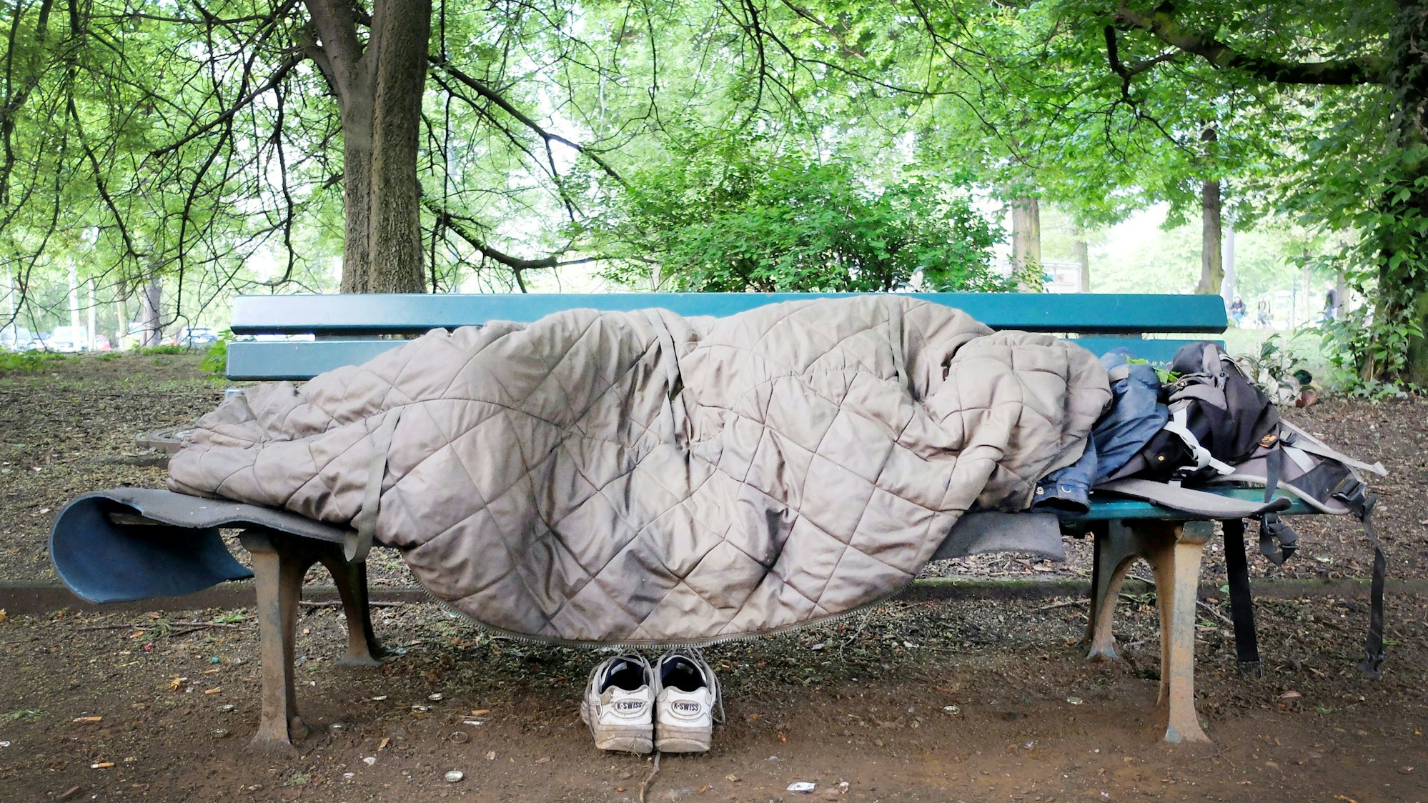 Ein Mann schläft auf einer Bank in einem Park.