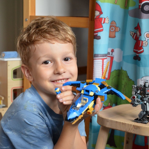Ein Junge zeigt ein von ihm gebasteltes Lego-Spielzeug.