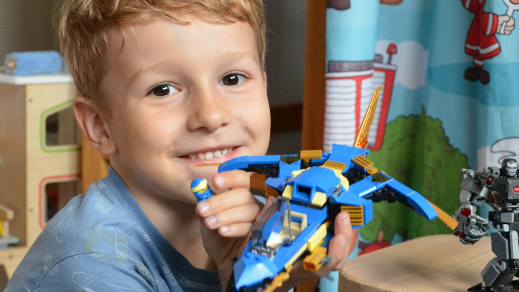 Ein Junge zeigt ein von ihm gebasteltes Lego-Spielzeug.