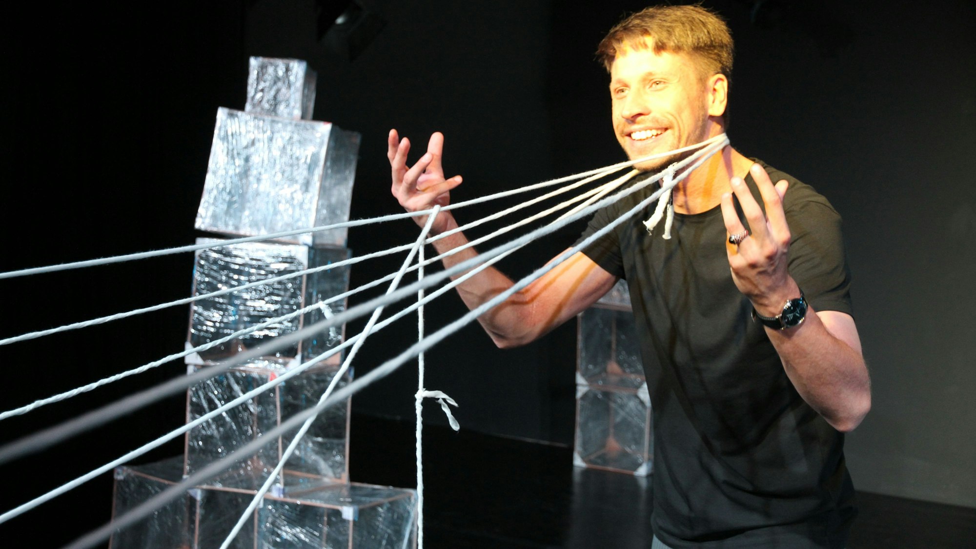 Ein Mann hält gespannte Wollfäden an den Händen