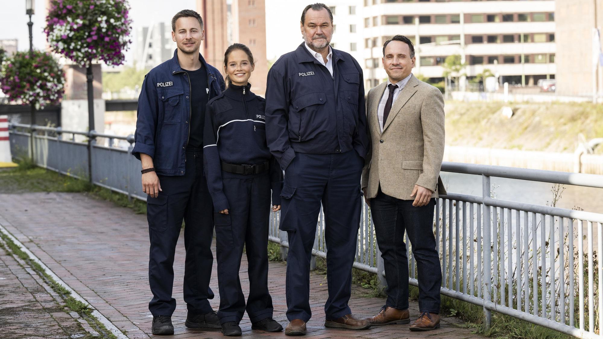 Vier Polizisten stehen an einem Zaun.