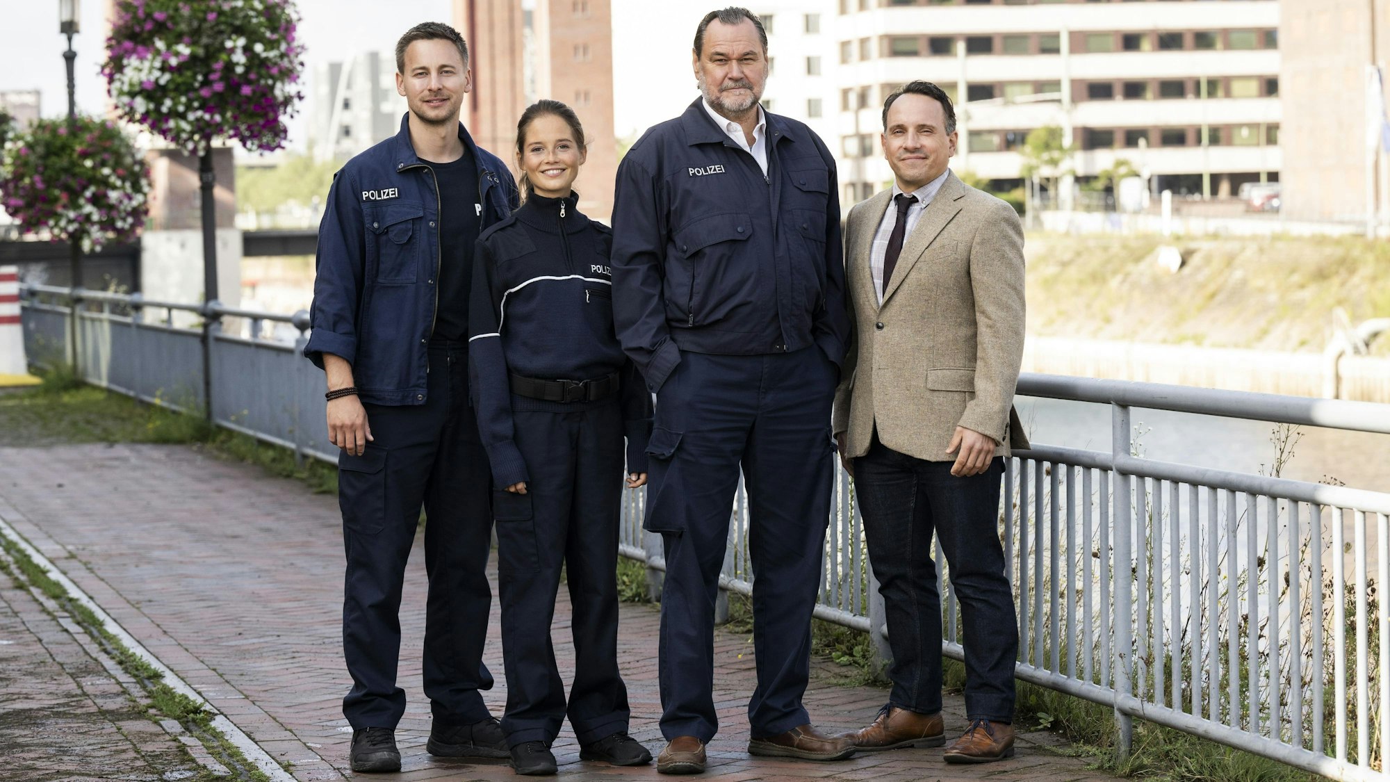 Vier Polizisten stehen an einem Zaun.