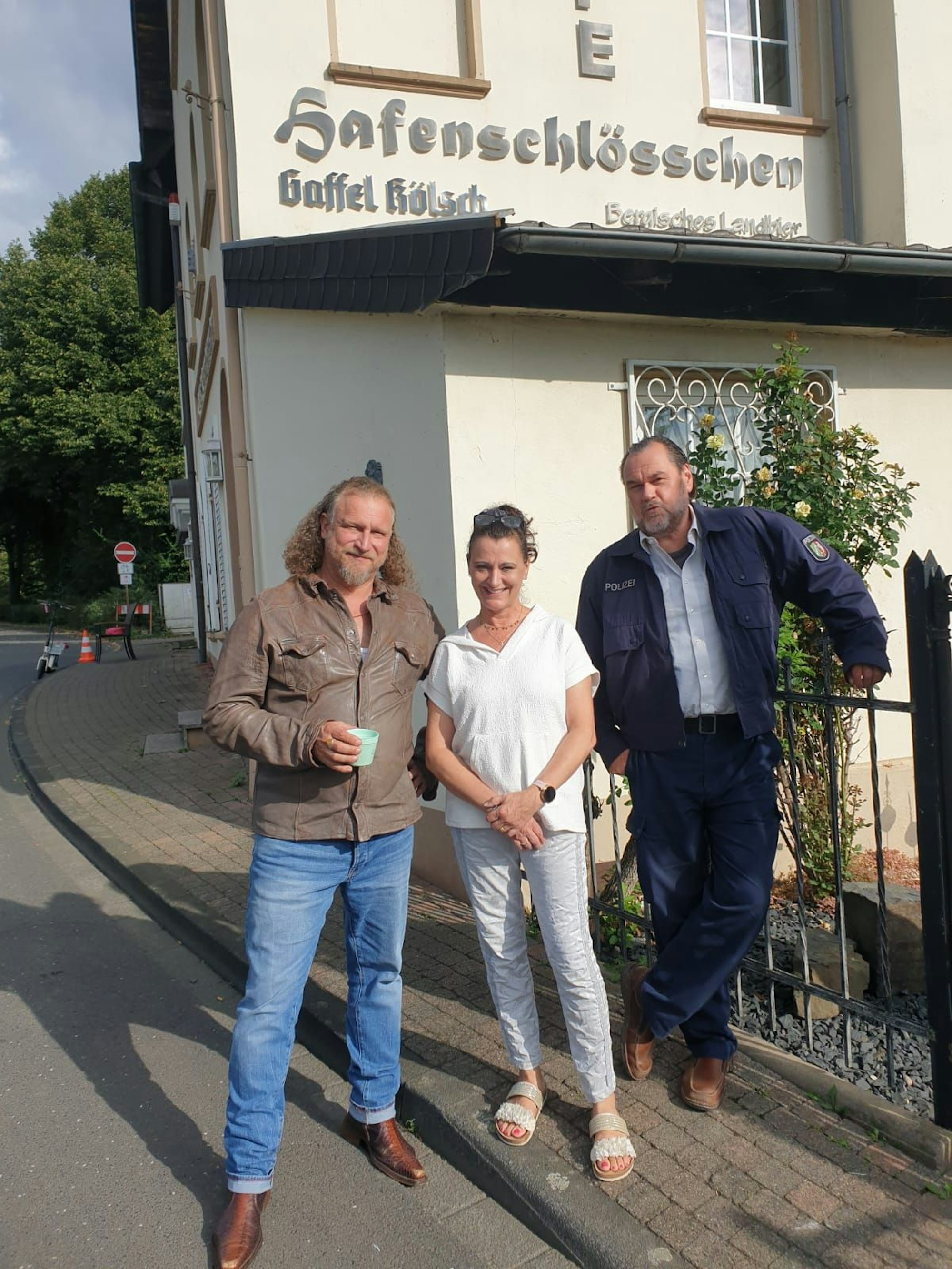 Zwei Männer und eine Frau stehen vor einem Gebäude.