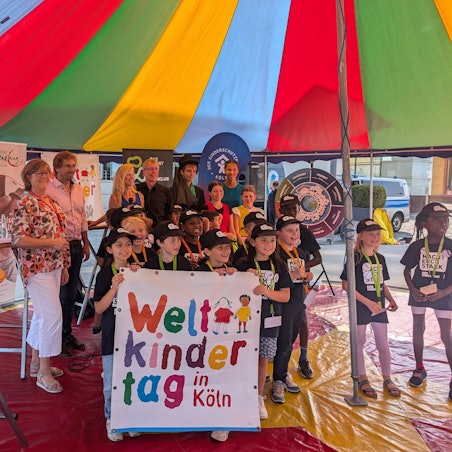 Das Organisationsteam der Weltkindertagsbühne am Harry-Blum-Platz, WDR-Moderatorin Insa Backe und der „Linoclub“-Kinderrat stehen in der Manege eines Zirkuszeltes.