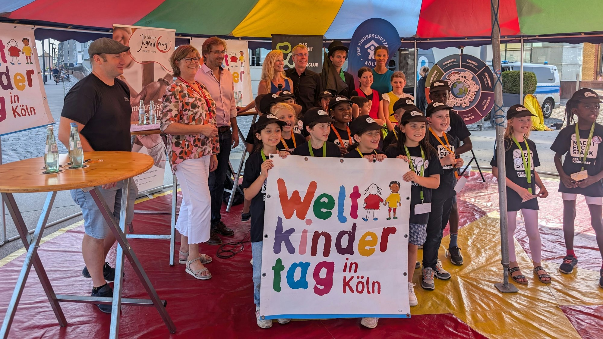 Das Organisationsteam der Weltkindertagsbühne am Harry-Blum-Platz, WDR-Moderatorin Insa Backe und der „Linoclub“-Kinderrat stehen in der Manege eines Zirkuszeltes.