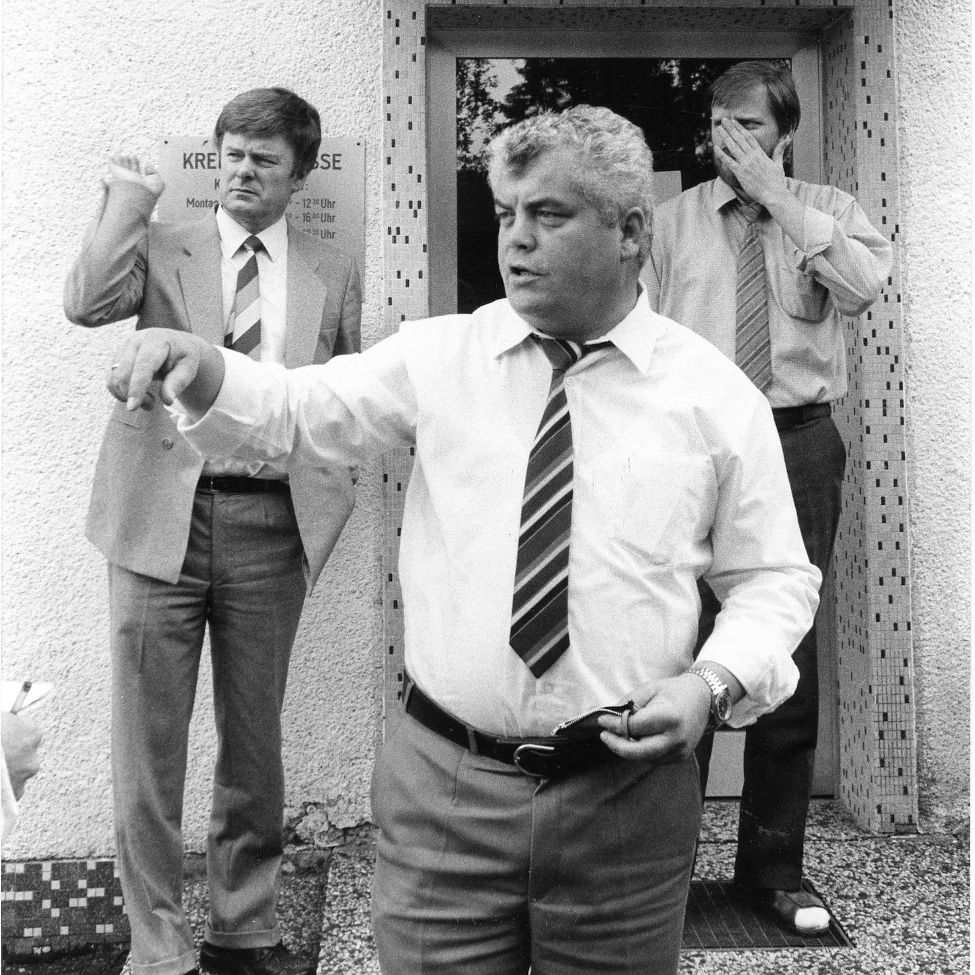 Das Foto zeigt drei Männer vor der Sparkassenfiliale.