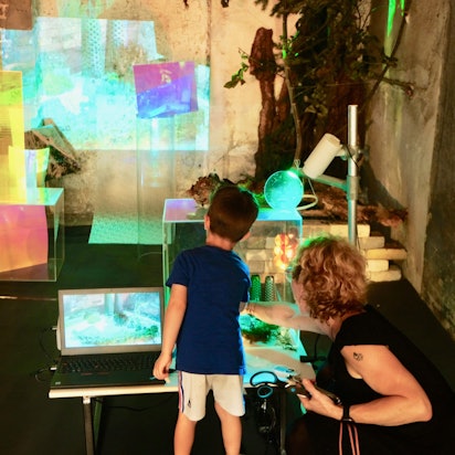 Ein junger Besucher erforscht an einer Ausstellungsstation Materialien und digitale Möglichkeiten.