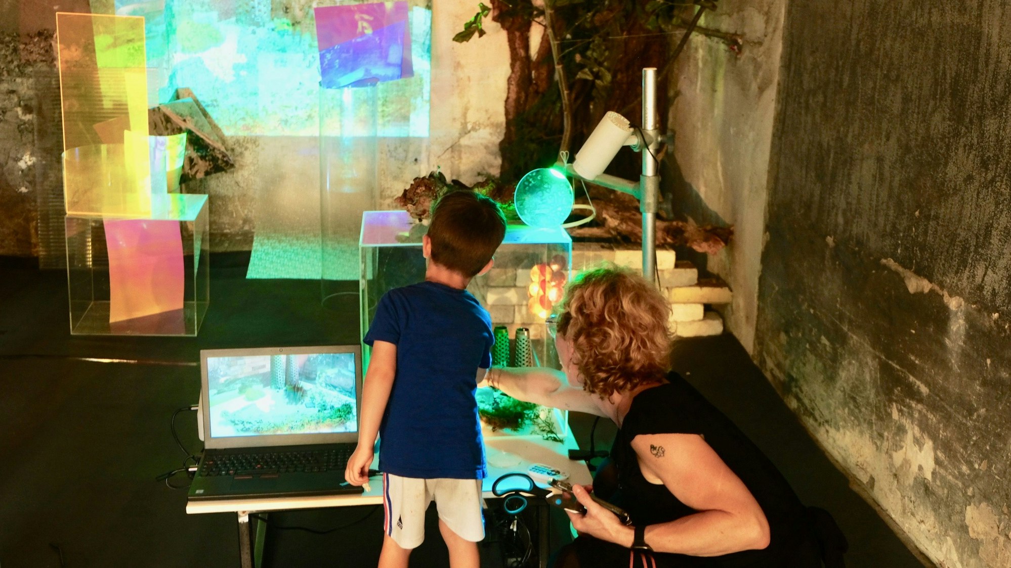 Ein junger Besucher erforscht an einer Ausstellungsstation Materialien und digitale Möglichkeiten.