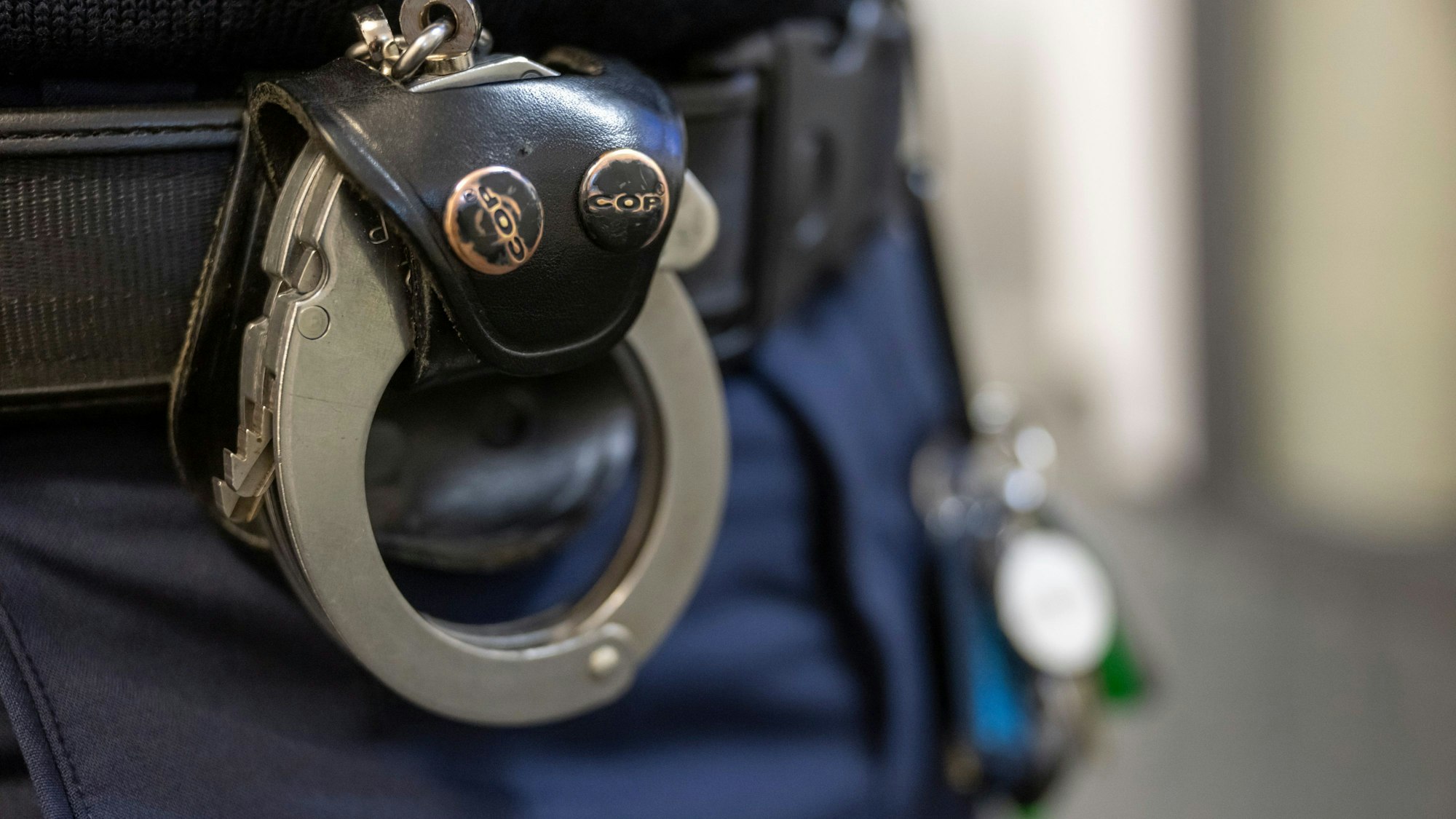 Eine Handschelle hängt am Gürtel eines Polizisten der Polizeiinspektion 11.