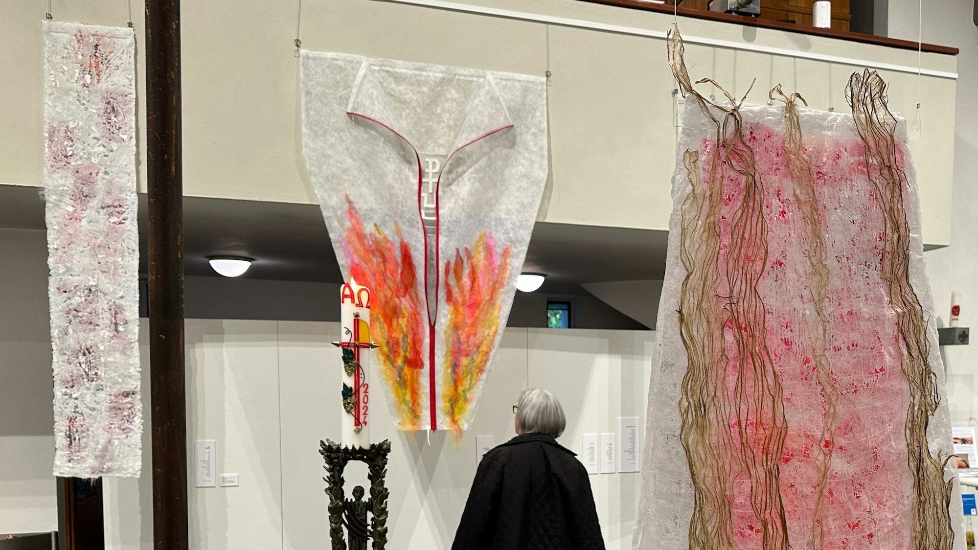 Eine Besucherin betrachtet einen bemalten Textilvorhang.