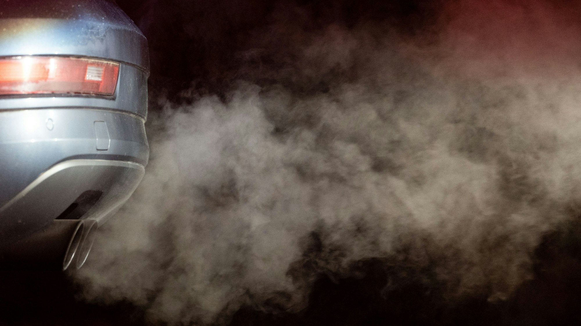 Abgase kommen aus dem Auspuff eines Autos und werden in der kalten Morgenluft sichtbar.