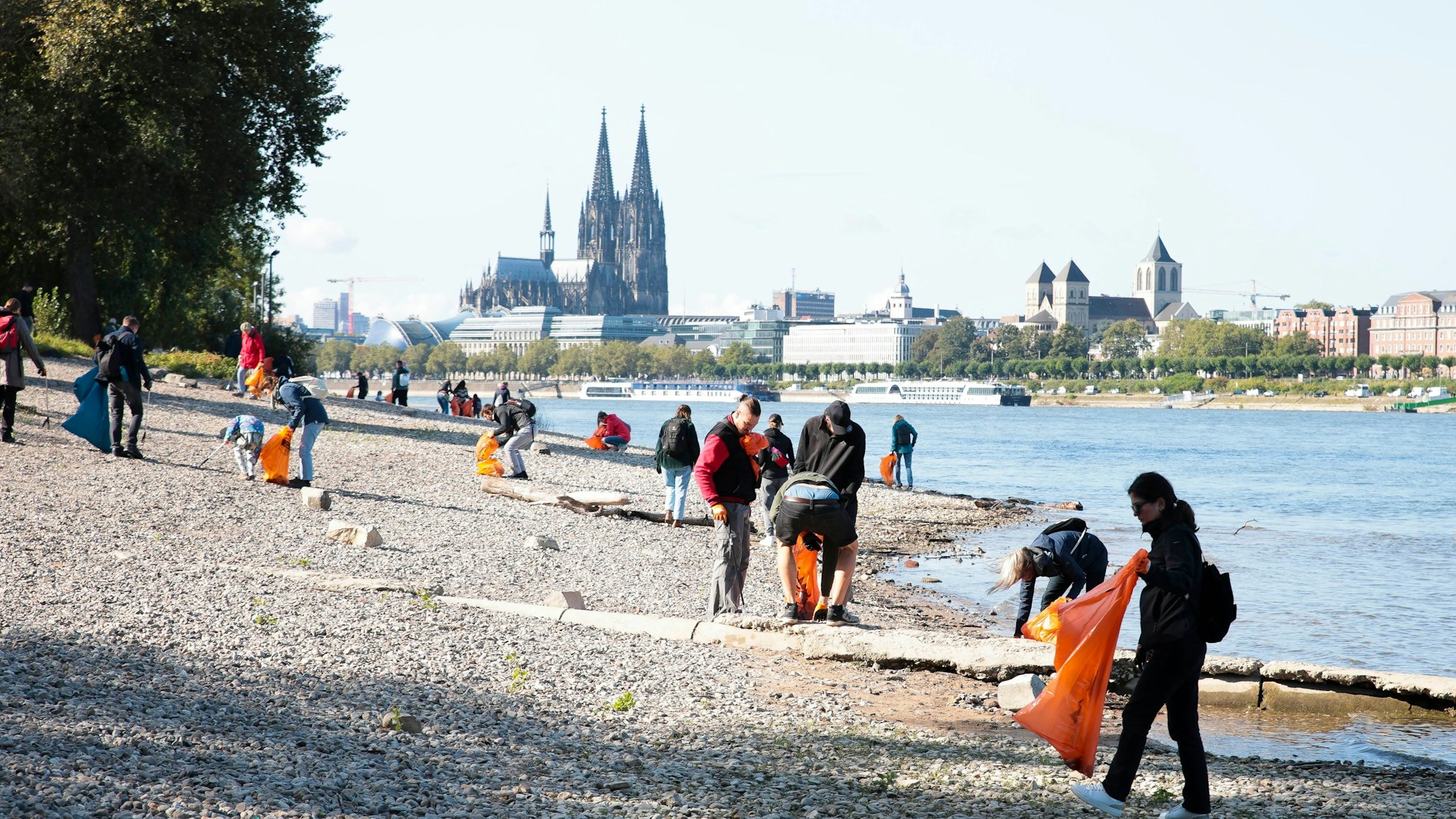 Menschen mit Mülltüte vorm Rhein