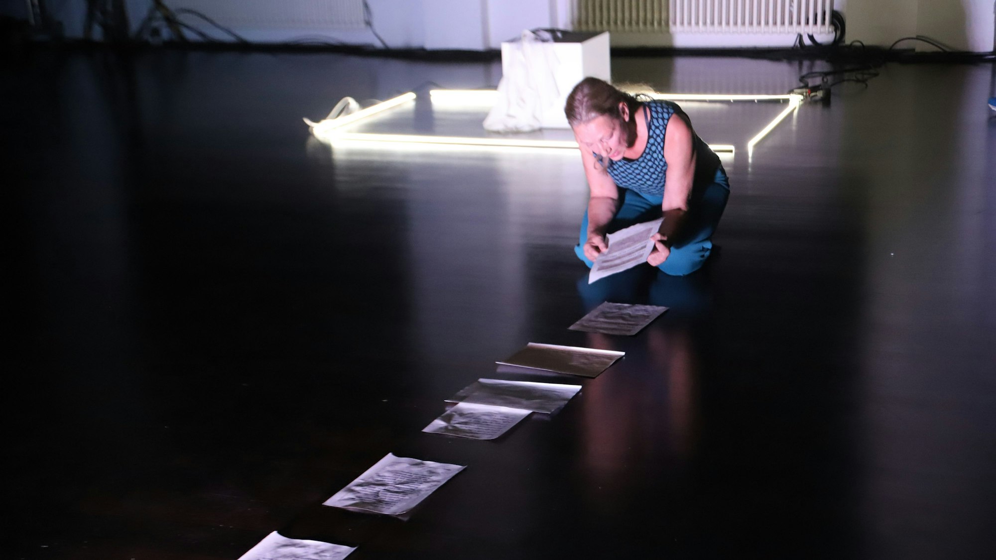 Eine Tänzerin breitet Papiere auf dem Boden aus.