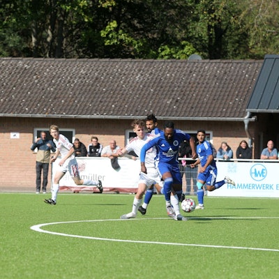 Ein Fußballer wird im Mittelkreis von einem Gegenspieler attackiert.