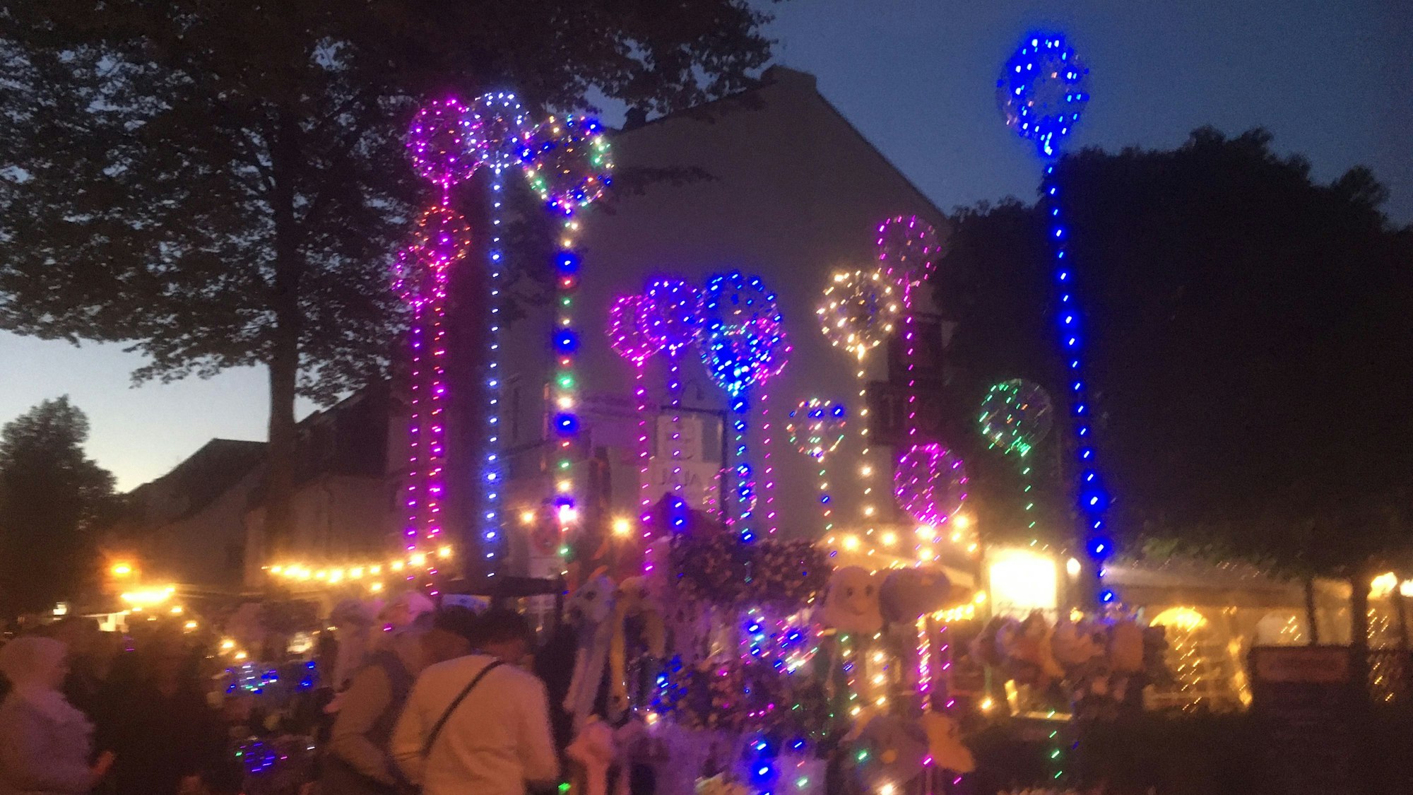 Luftballons mit bunten Lichterketten leuchten am Abend.