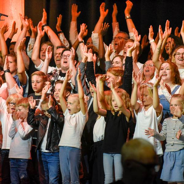 Zahlreiche Kinder und Erwachsene werfen die Arme in die Luft.