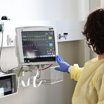 Eine Pflegerin schaut in einem Krankenzimmer im Klinikum Stuttgart auf einen Monitor einer Patientin.