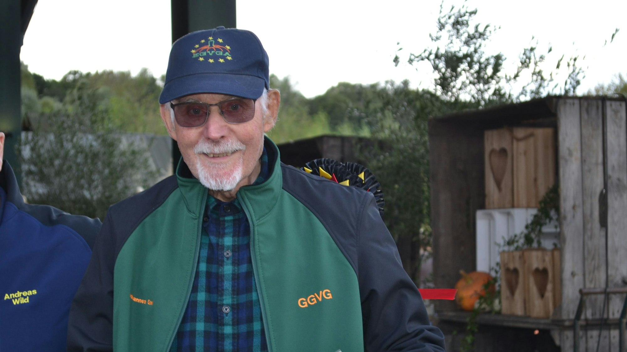 Ein älterer Mann in grüner Jacke und mit Käppi.