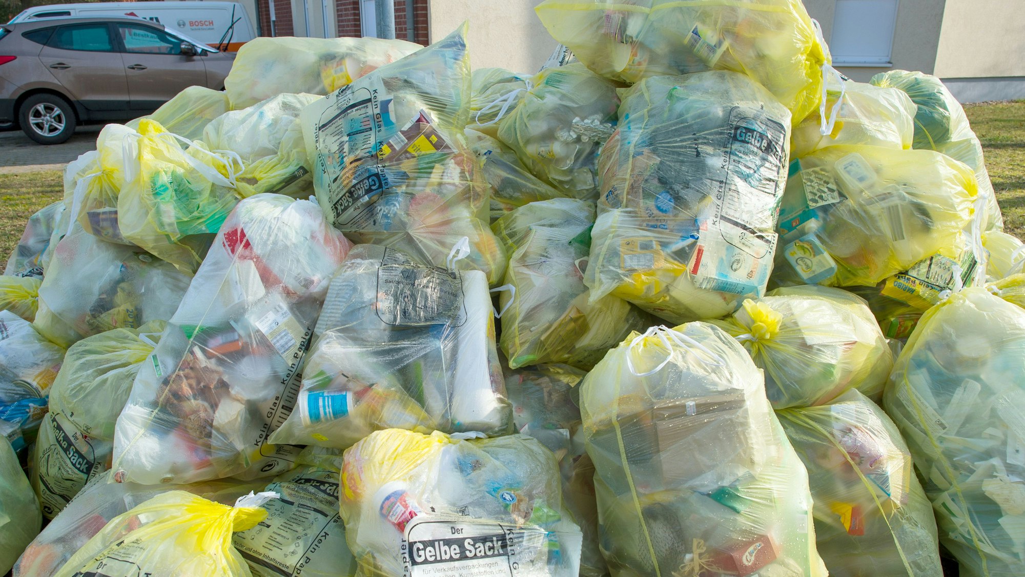 Ein Berg mit Gelben Säcken, gefüllt mit Verpackungsabfall, liegt auf einem Grundstück zu Abholung bereit. (Archivbild)
