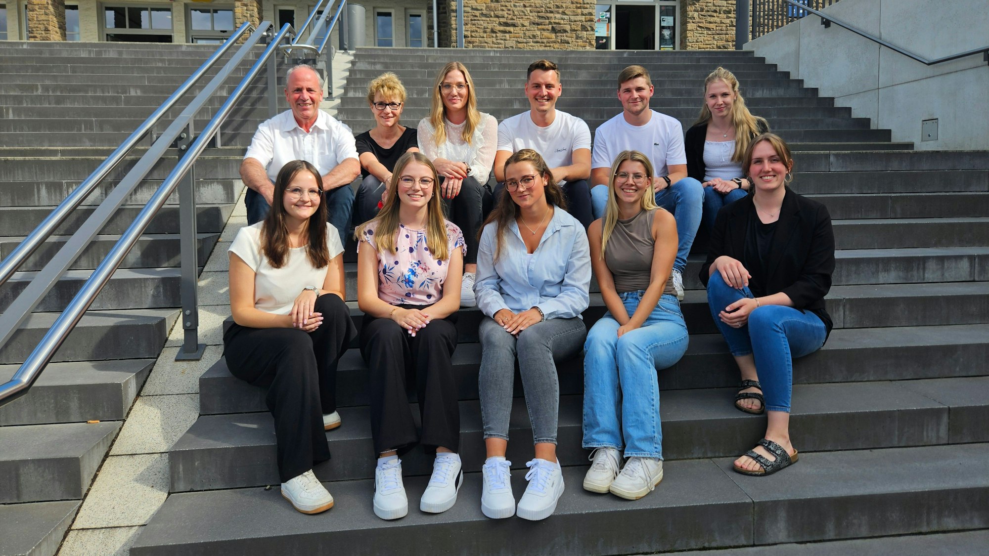 Die Azubis der Gemeinde Kall und Nina Pützer (hinten 3.v.l.), Anja Schlösser (2.v.l.) und Hermann-Josef Esser (l.) sitzen auf der Treppe vor dem Bahnhof Kall.