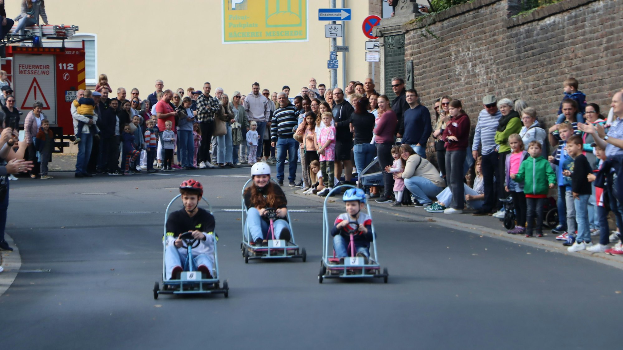 Auf dem Bild sind Kinder und Zuschauer beim Seifenkistenrennen zu sehen.