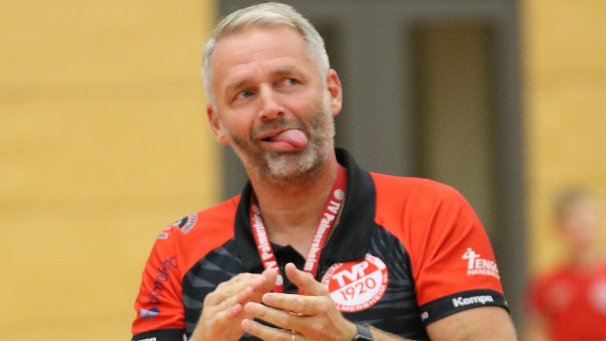 Der Trainer klatscht in die Hände, seine Zunge hat er ausgestreckt.