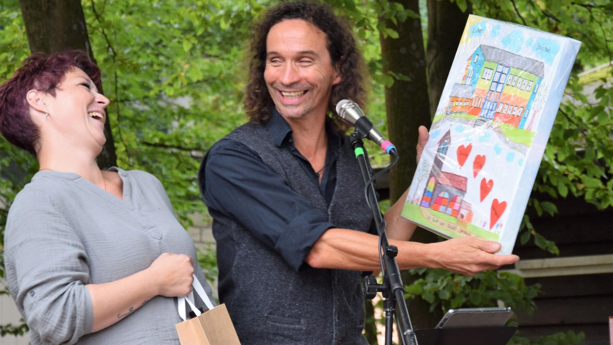 Jasmin Heller überreicht dem Musiker Stefan Brings das von den OGS-Kindern gemalte Bild.