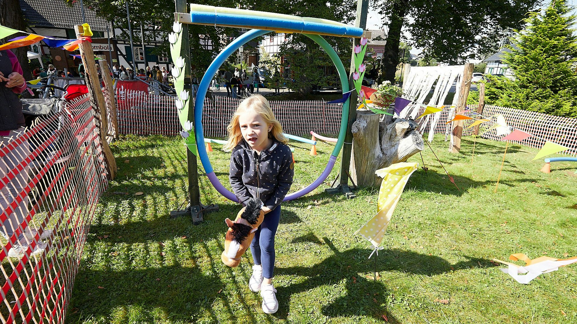 Frieda springt mit ihrem Steckenpferd durch einen Reifen.