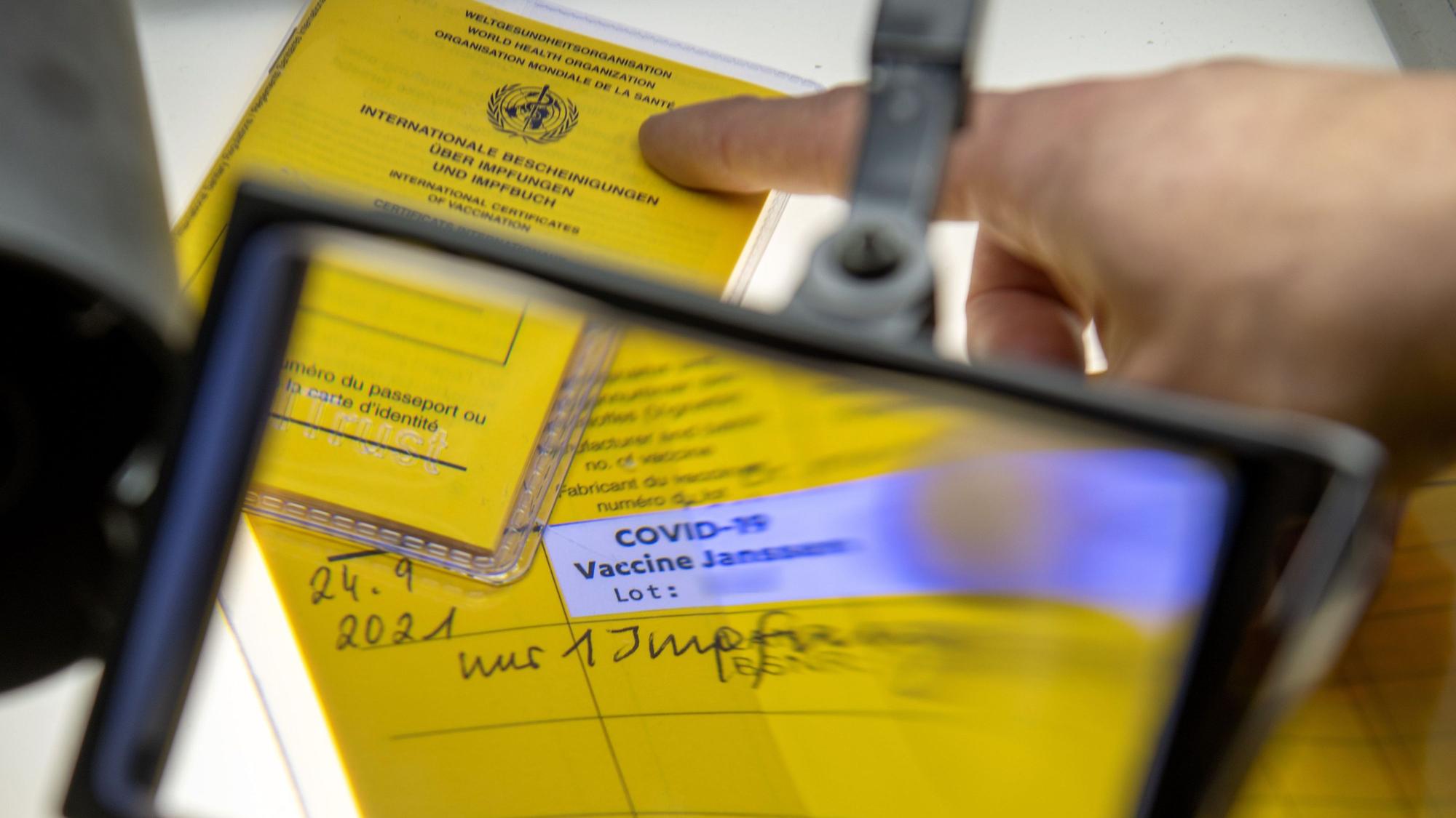 Ein Impfpass unter der Lupe mit dem Eintrag einer Corona-Impfung