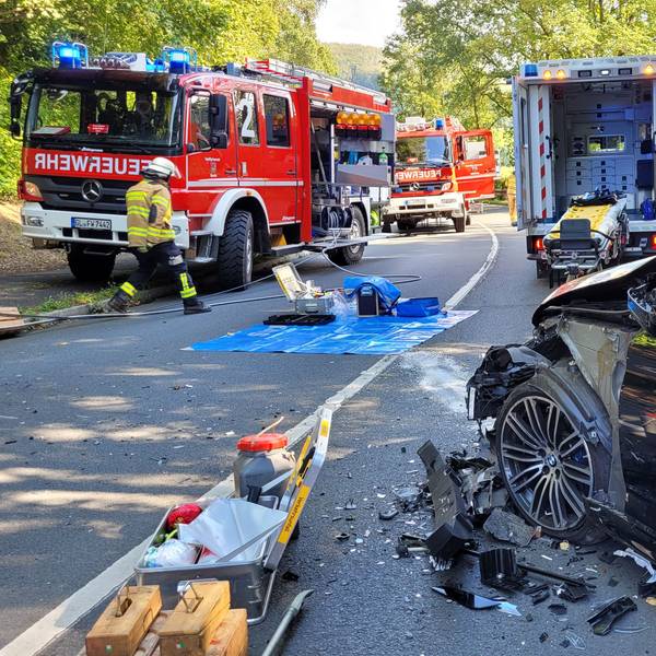 Ein Auto mit Totalschaden steht vor Feuerwehrfahrzeugen.